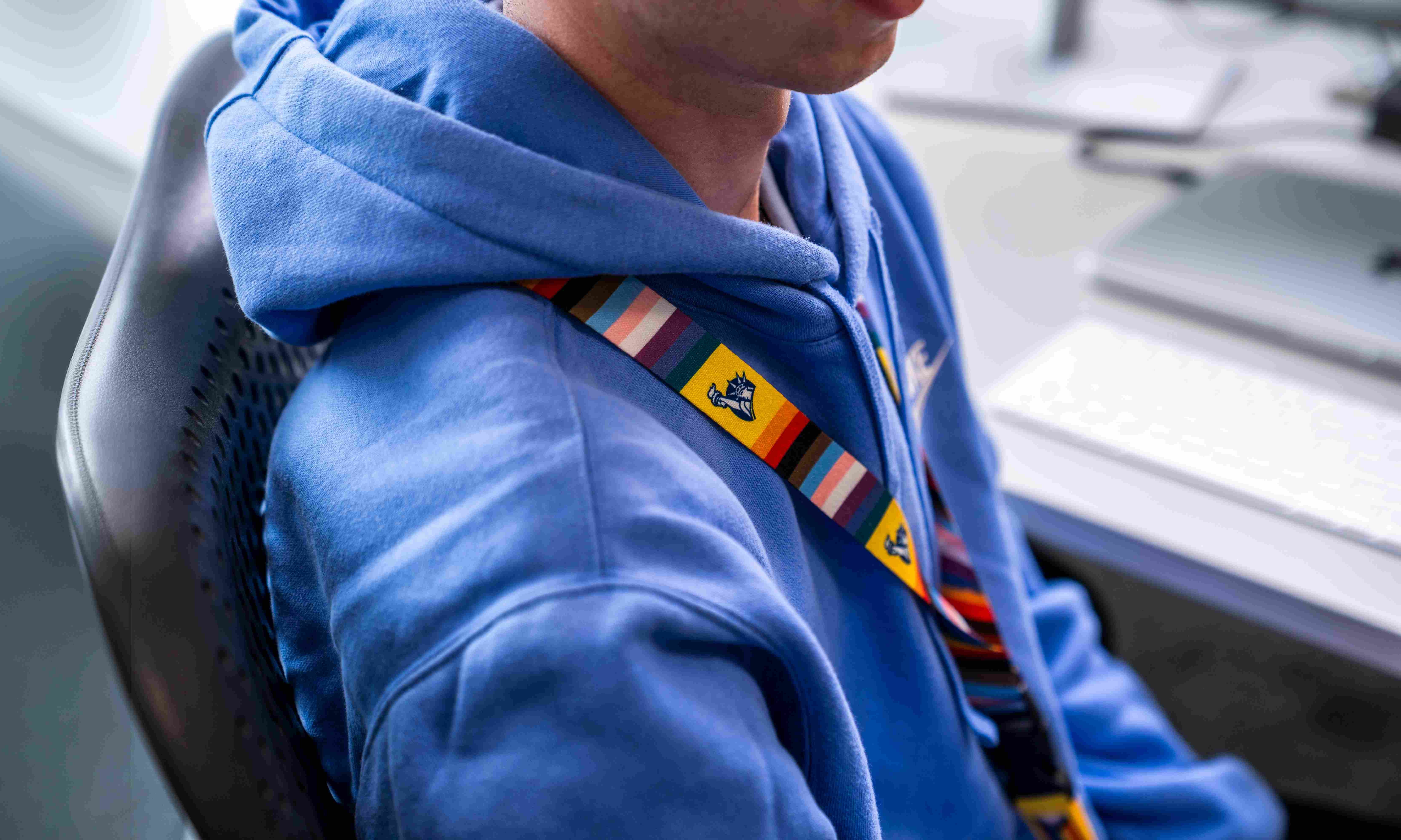 Employee sitting at a desk, zoomed into their Pride lanyard