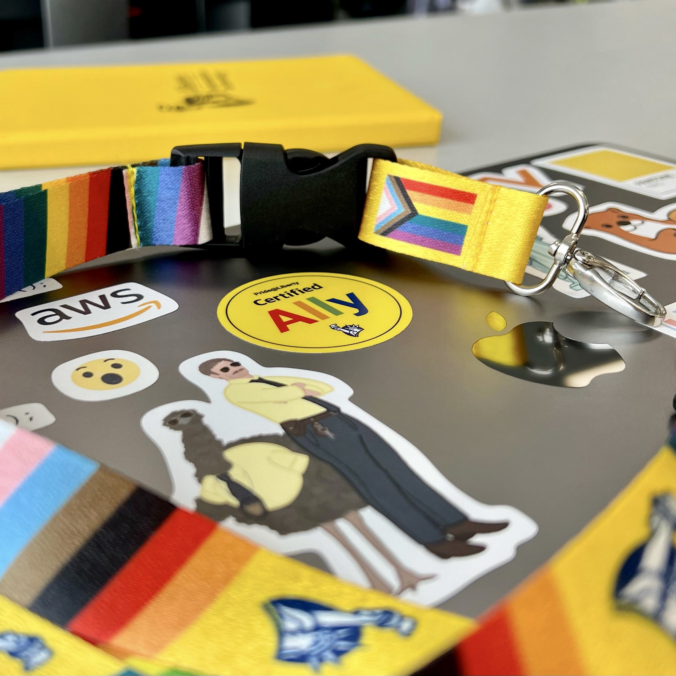 Pride lanyards and a laptop with various stickers