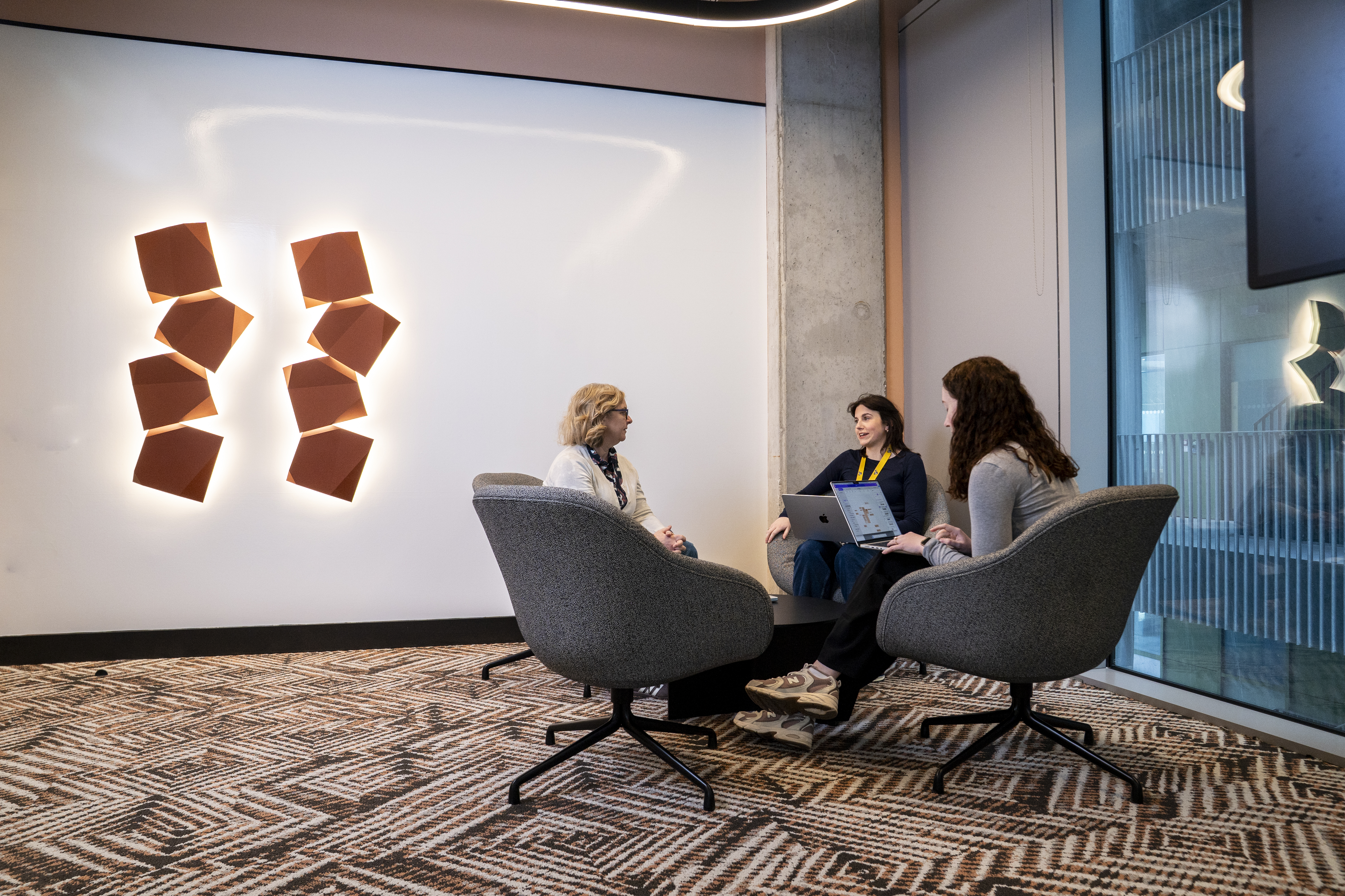 Employees meeting in an informal collaboration space in a Liberty IT office.
