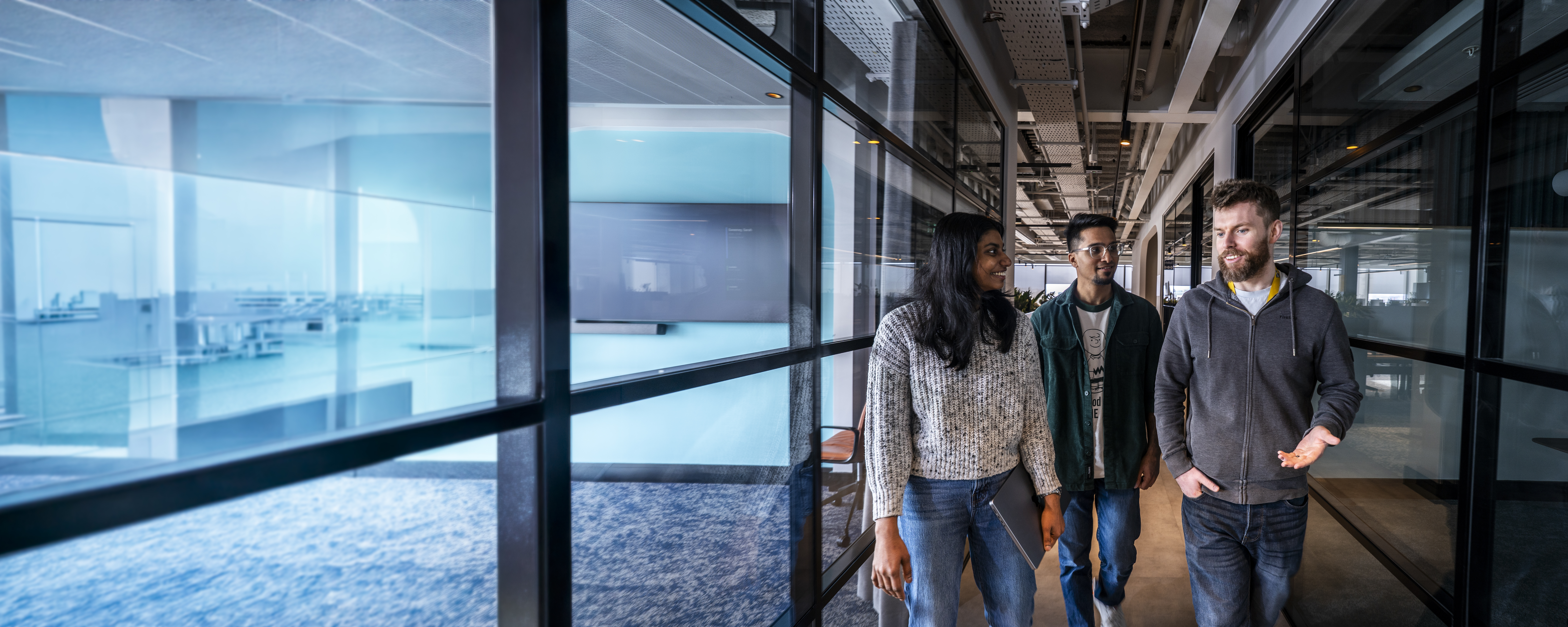 Employees walking and talking together in a Liberty IT office corridor.