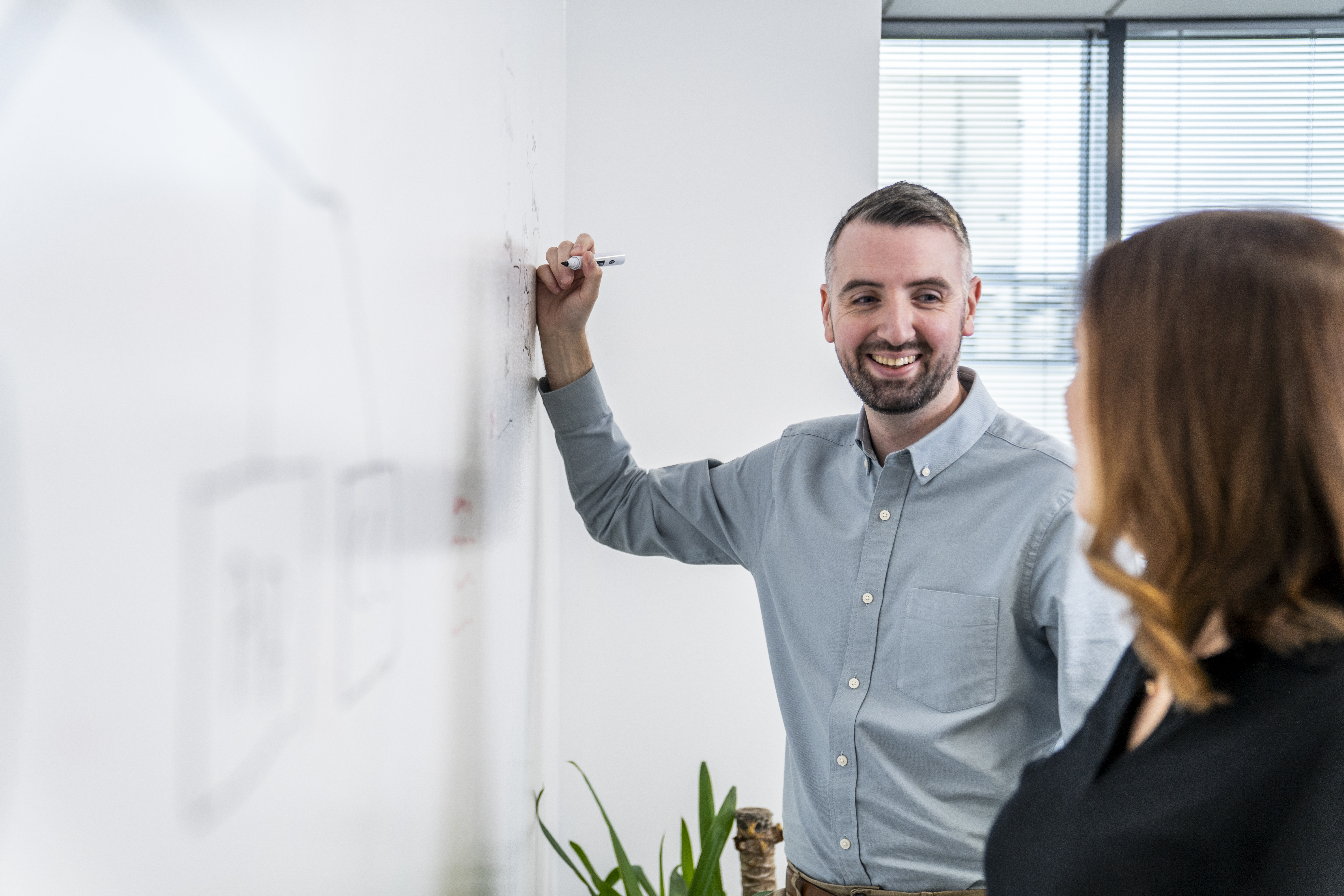 Liberty IT employee writing on a whiteboard with a colleague
