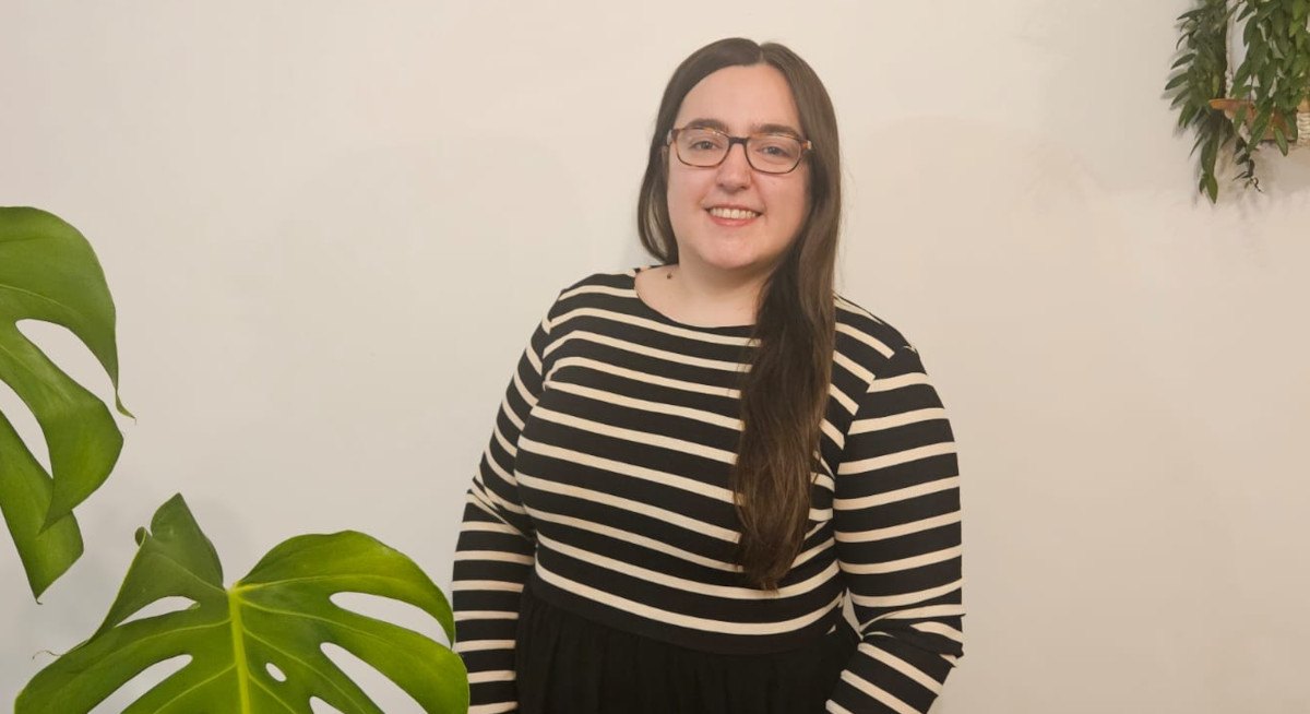 Sarah, Software Engineer smiling next to greenery