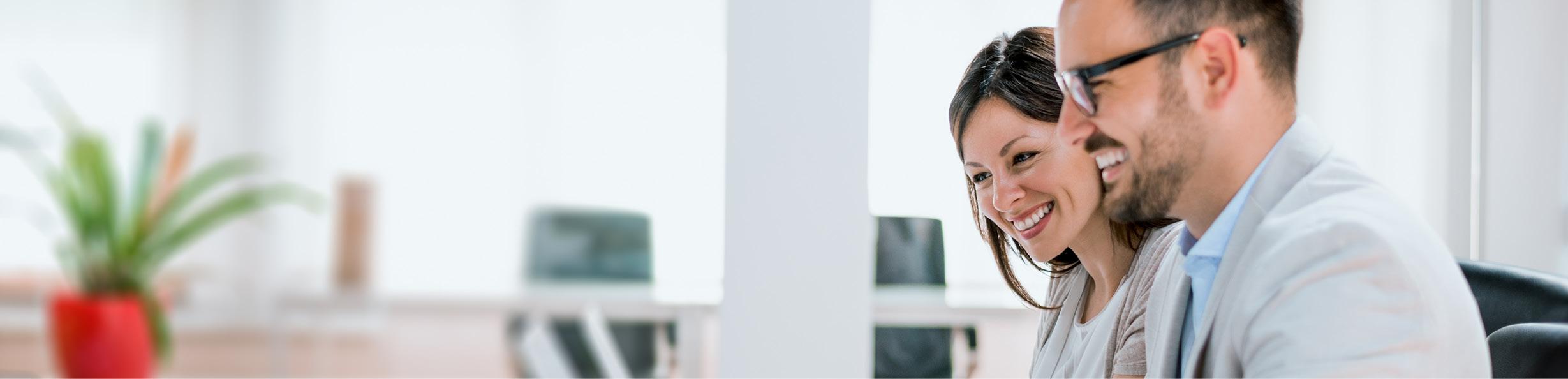 Photo of a woman and man sitting in an office, looking downwards